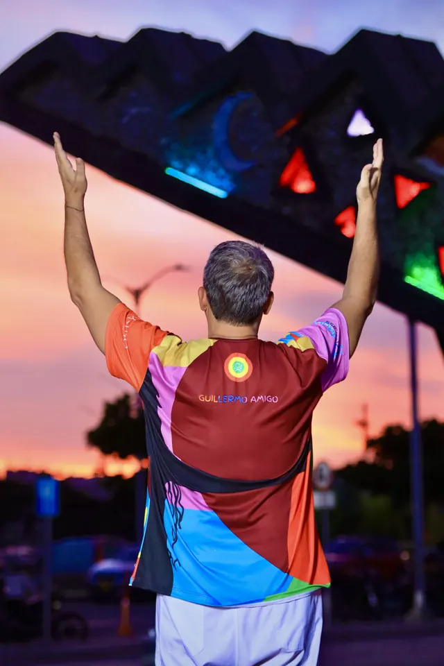 Cantor con los brazos arriba al atardecer en el Malecón