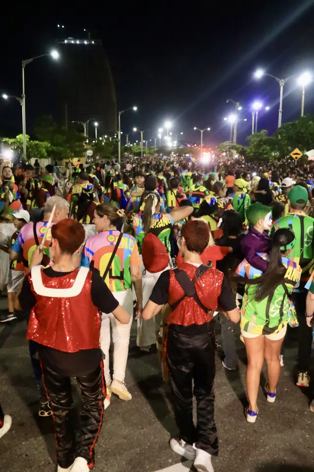 Comparsa con trajes brillantes desfilando de noche